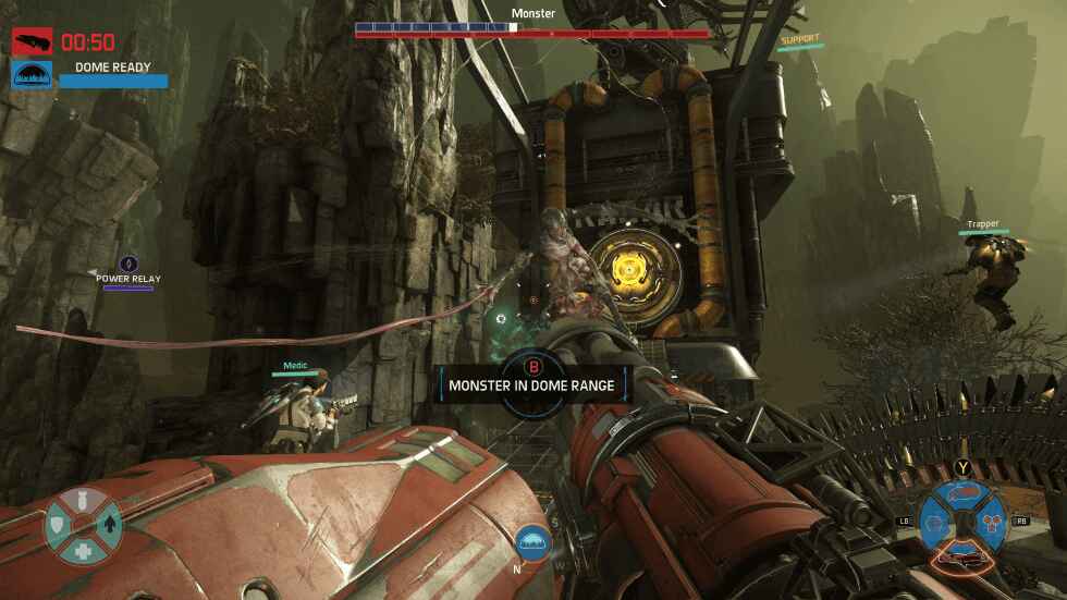 Gameplay of Evolve shows a large monster being attacked by three players with a large structure behind it